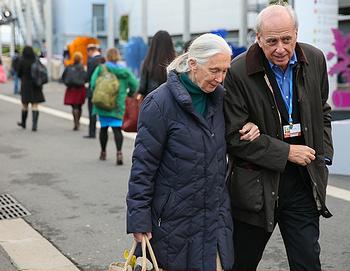 Dame Jane Goodall, with Cow in her carrying bag, walks with a friend in the hallway of the COP21 conference venue at Paris-LeBourget, Dec. 2015 (Photo courtesy Earth Negotiations Bulletin)