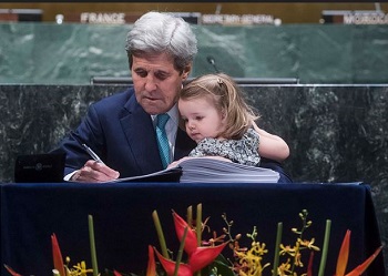 United States Secretary of State John Kerry, with grand-daughter in his arms, signs the Paris Agreement, April 22, 2016 (UN Photo by Amanda Voisard)